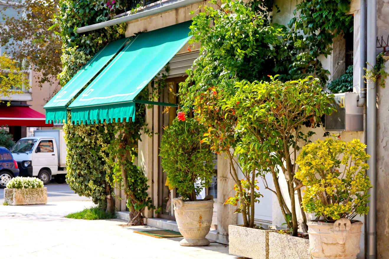 Storefront with green fabric awnings over the windows