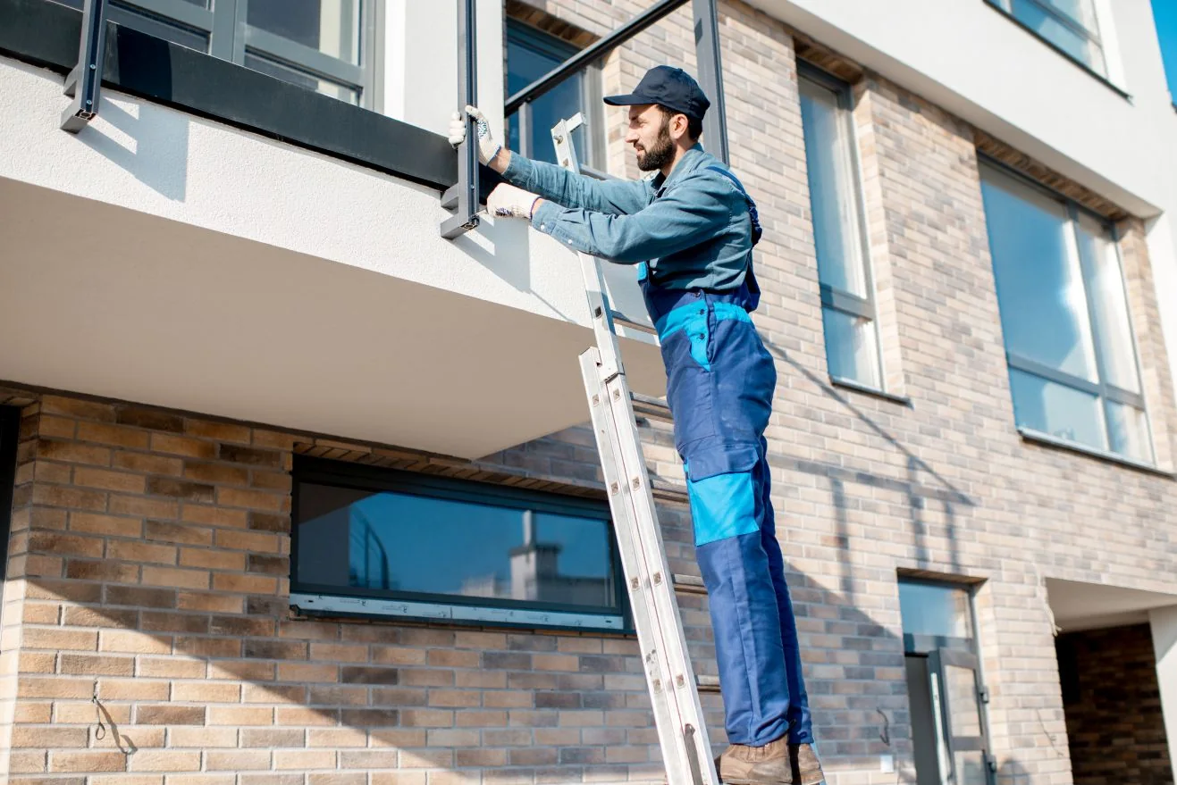 Worker on a ladder checking the front of a building